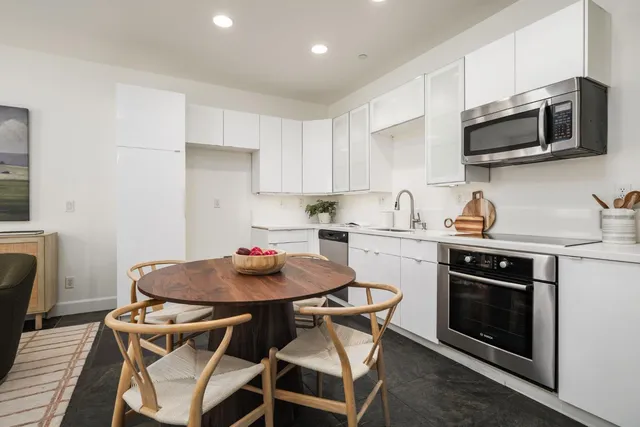 a kitchen with stainless steel appliances a stove a table and chairs