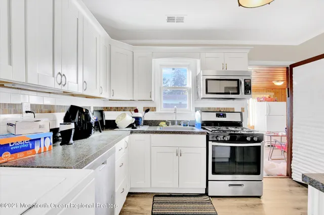 a kitchen with stainless steel appliances granite countertop a stove a sink and a white refrigerator