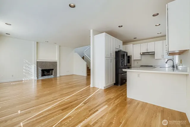 a view of a kitchen with a sink dishwasher a refrigerator and cabinets with wooden floor