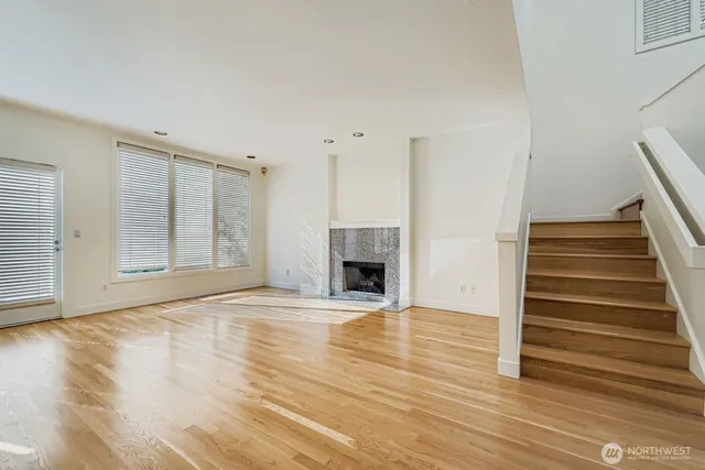 a view of an empty room with wooden floor fireplace and a window