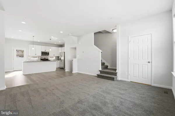a view of kitchen with refrigerator and white cabinets