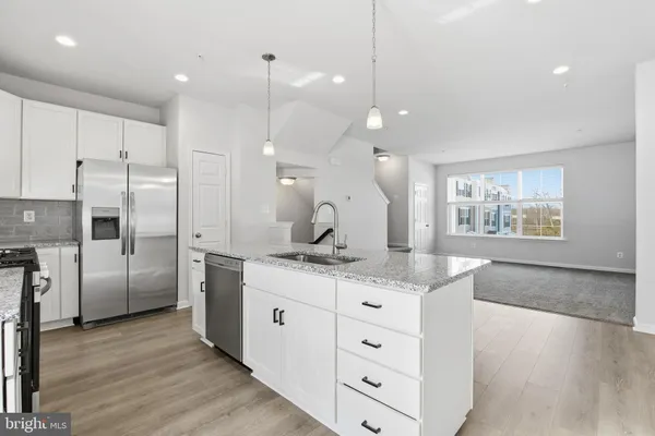 a kitchen with stainless steel appliances kitchen island wooden floors refrigerator and cabinets