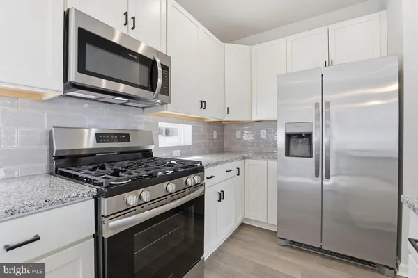 a kitchen with stainless steel appliances granite countertop a stove microwave and refrigerator