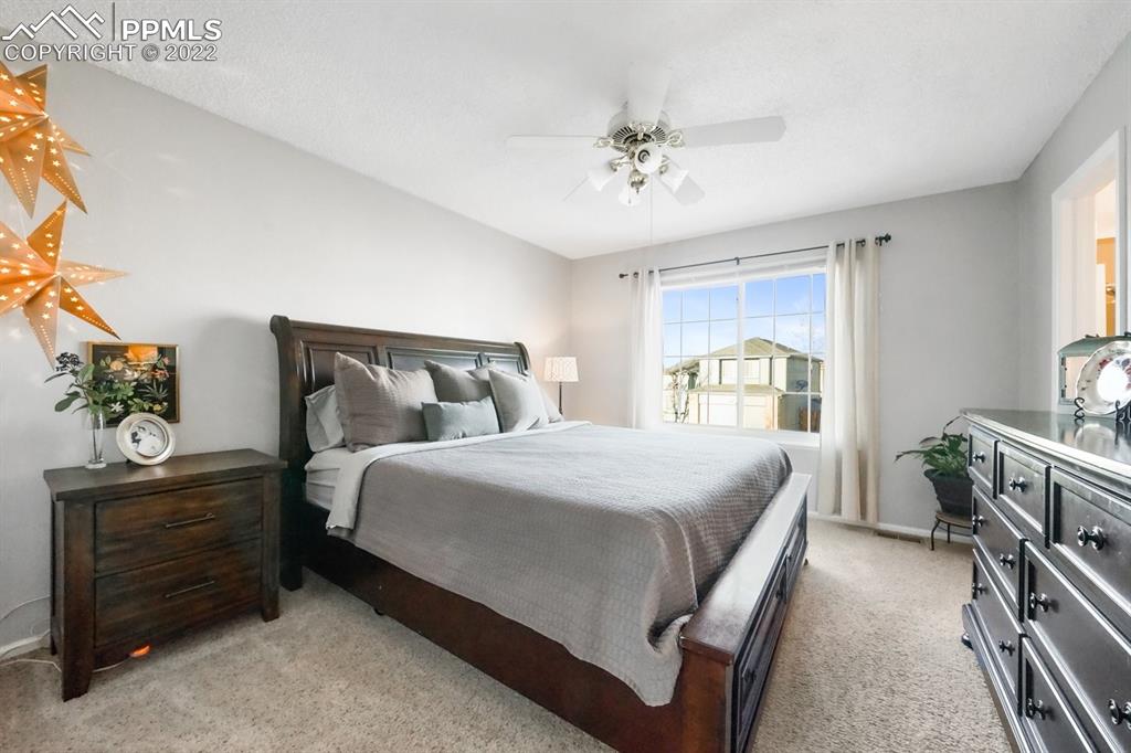 5145 Slickrock Drive Colorado Springs, CO 80923 - Photo 20 of 33 a bedroom with a bed and a chandelier