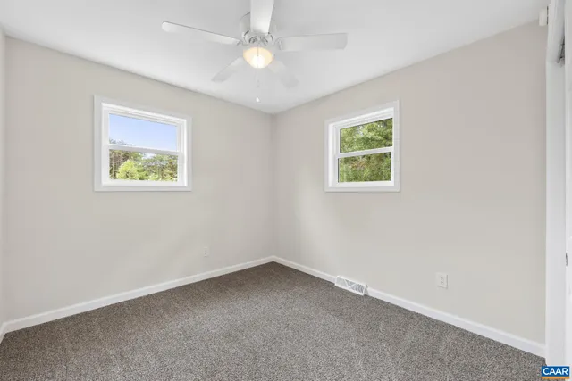an empty room with a window and a ceiling fan