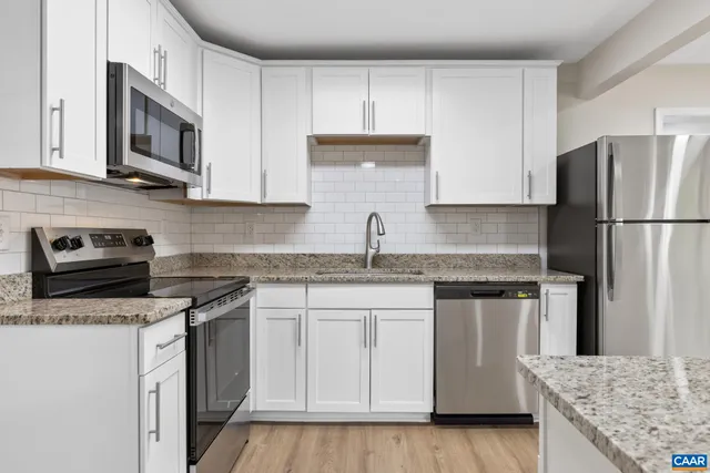 a kitchen with granite countertop a sink stove and refrigerator