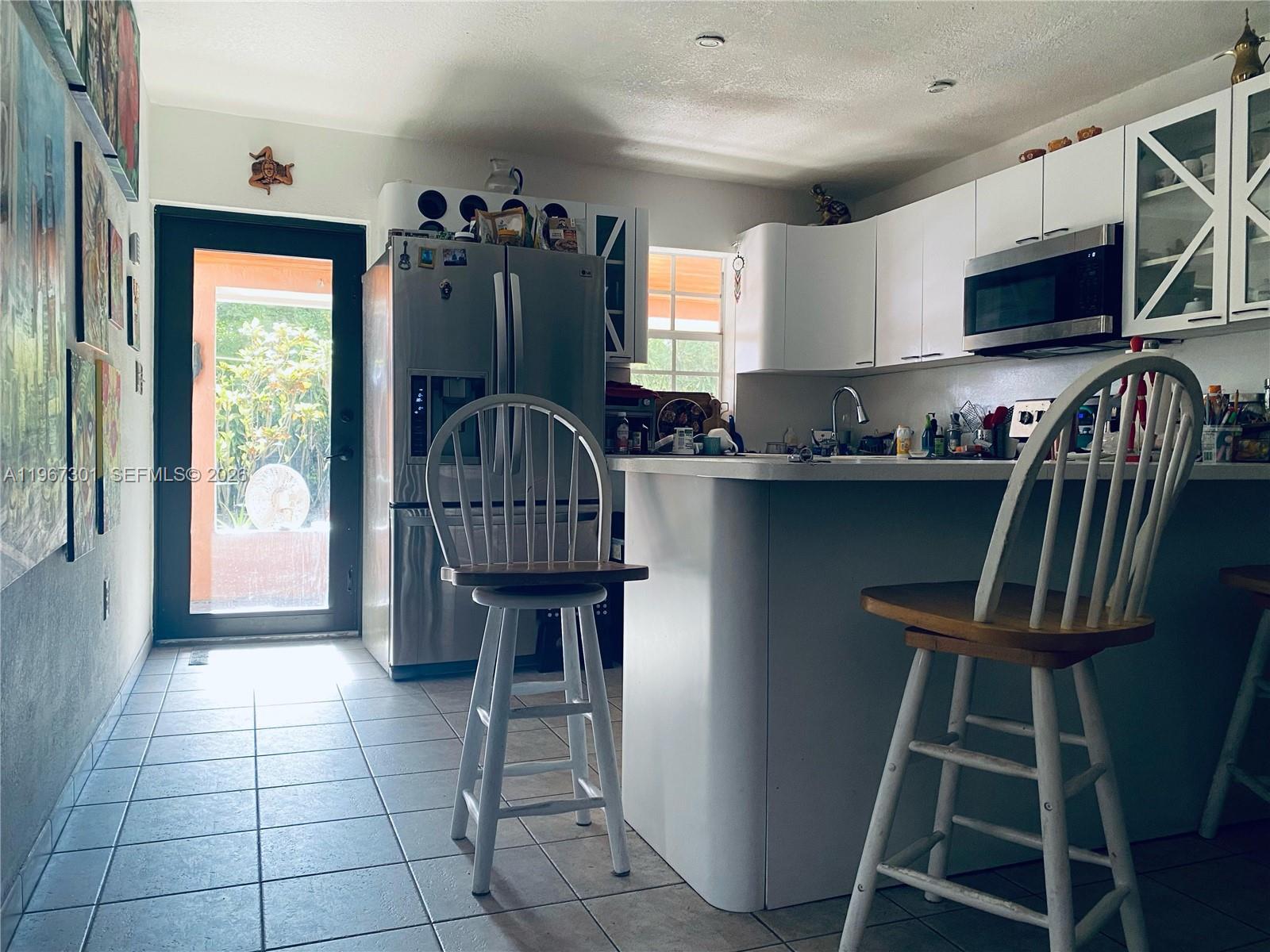 1760 Northeast 144th Street Miami, FL 33181 - Photo 41 of 83 a kitchen with granite countertop a stove a sink dishwasher a dining table and chairs with wooden floor