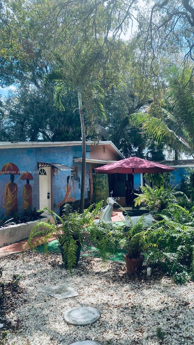 1760 Northeast 144th Street Miami, FL 33181 - Photo 65 of 83 a view of a house with a yard and lawn chairs under an umbrella