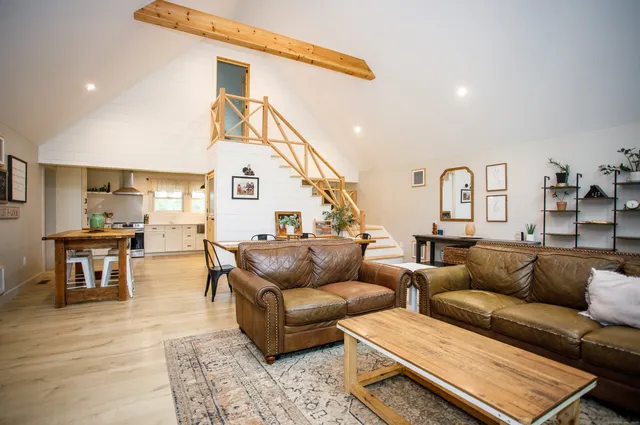 a living room with furniture kitchen view and a wooden floor