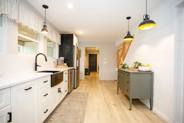 a view of a kitchen with kitchen island a sink wooden floor and a large window