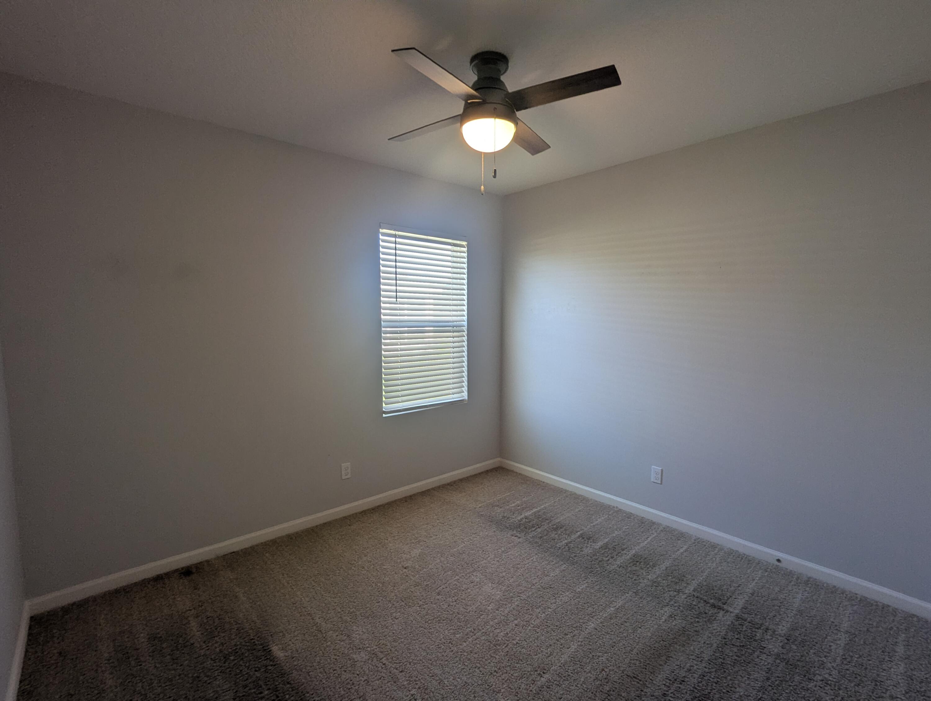 284 Southwest Ridgecrest Drive Port St. Lucie, FL 34953 - Photo 4 of 16 an empty room with a window and a fan
