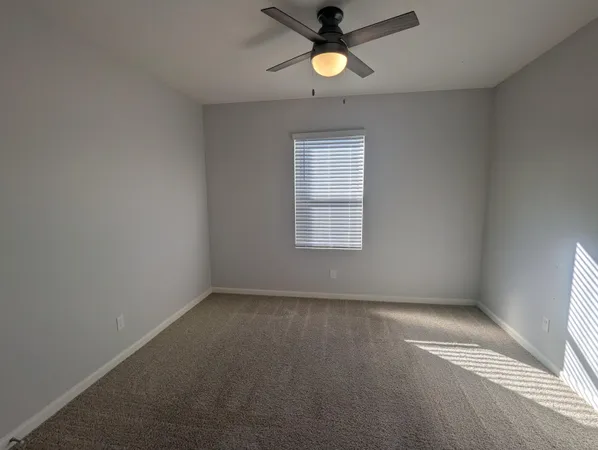 an empty room with a window and a fan