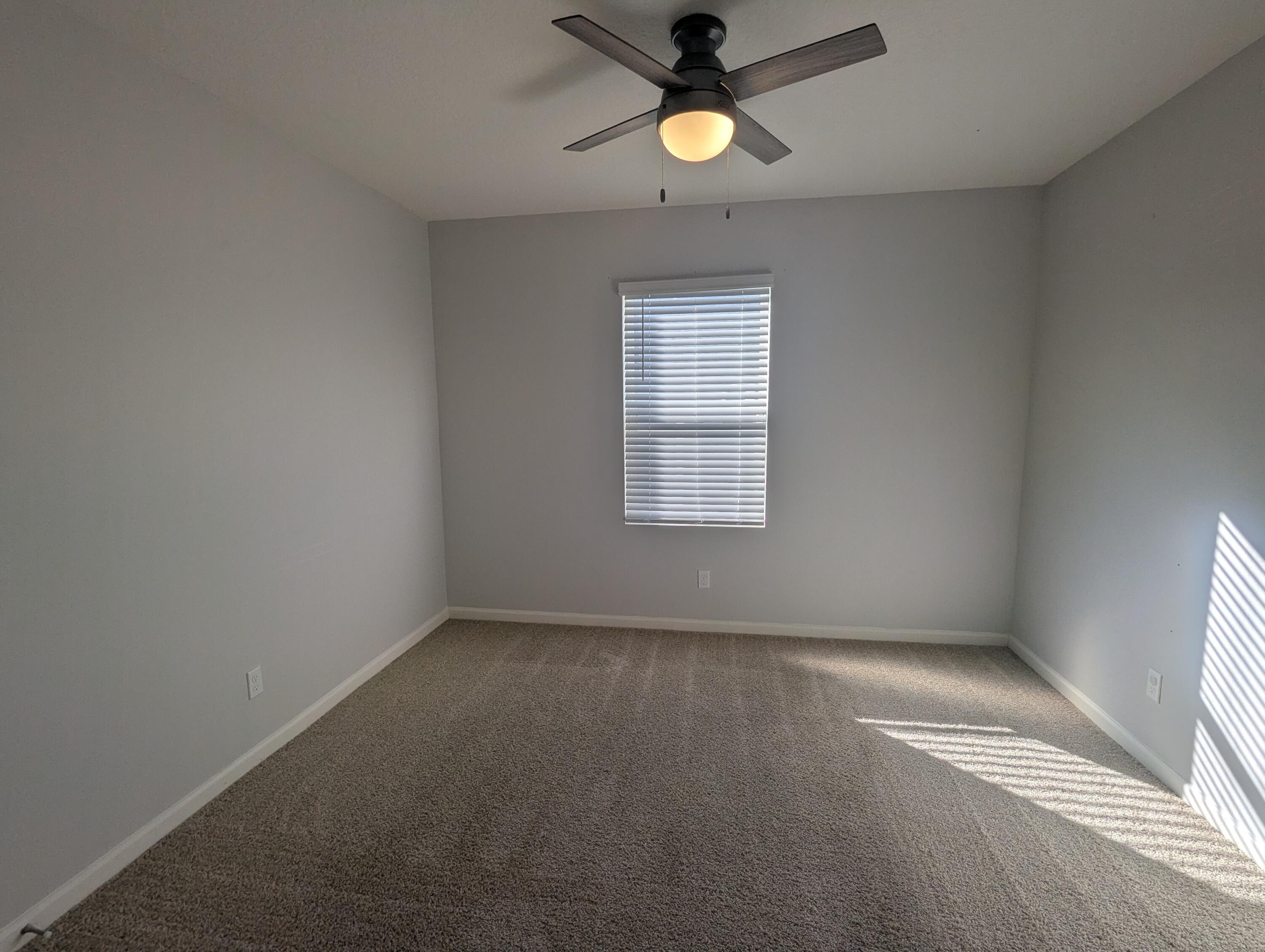 284 Southwest Ridgecrest Drive Port St. Lucie, FL 34953 - Photo 5 of 16 an empty room with a window and a fan