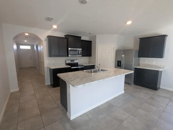 a large kitchen with stainless steel appliances a sink and a microwave