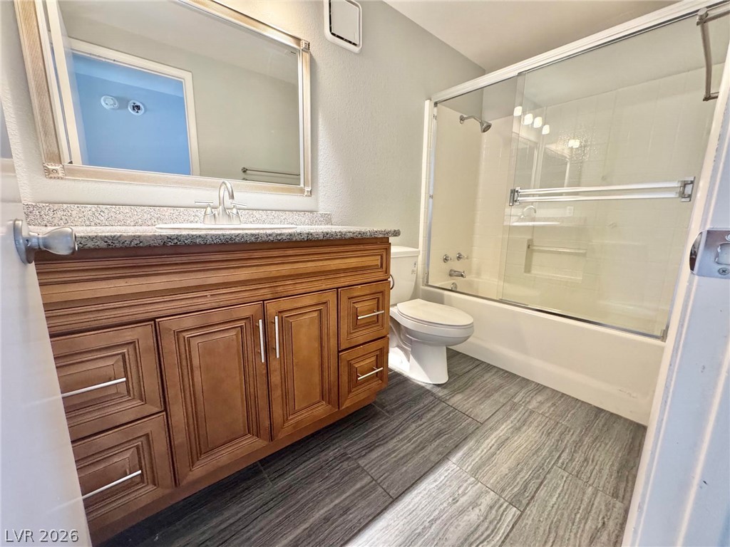 5304 Runningbrook Road Las Vegas, NV 89120 - Photo 17 of 22 Rich wood cabinetry and granite countertops elevate this modern bathroom with a glass-enclosed shower.