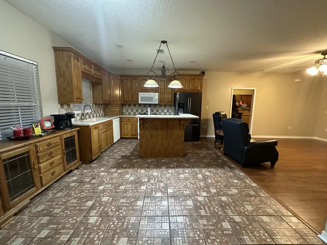 a large kitchen with kitchen island granite countertop a stove a sink dishwasher and a black refrigerator