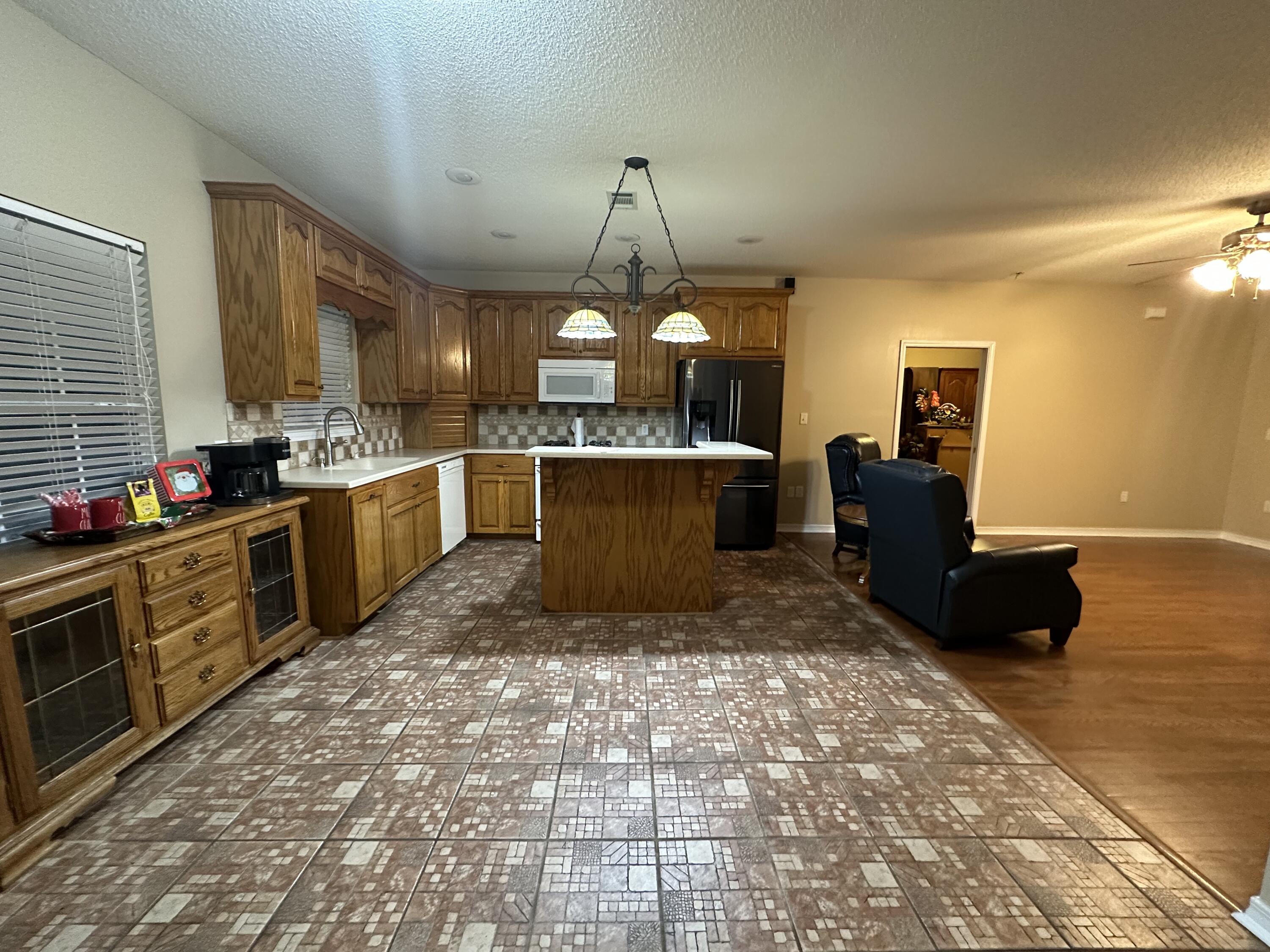 5771 Flora Lee Lane Crestview, FL 32539 - Photo 5 of 66 a large kitchen with kitchen island granite countertop a stove a sink dishwasher and a black refrigerator