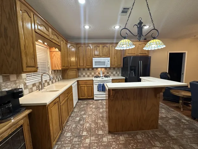 a large kitchen with a counter space a sink appliances and cabinets