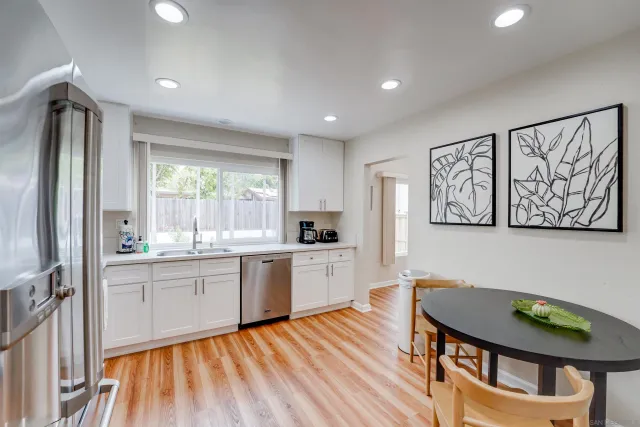 a kitchen with stainless steel appliances granite countertop a stove a sink dishwasher and a refrigerator with wooden floor