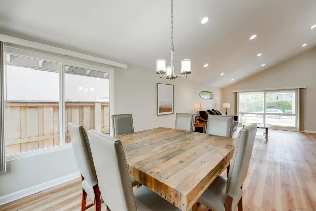 a dining room with wooden floor a chandelier a wooden table and chairs