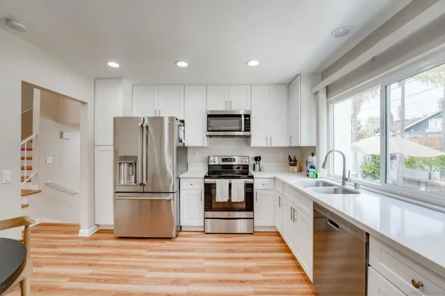 a kitchen with kitchen island granite countertop a refrigerator oven a sink and wooden floors