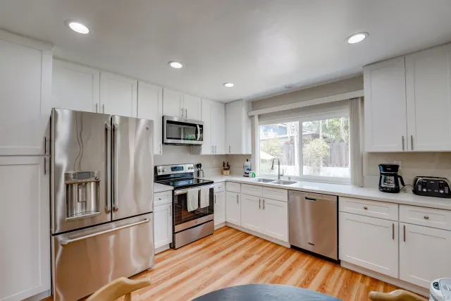 a kitchen with white cabinets stainless steel appliances and a window