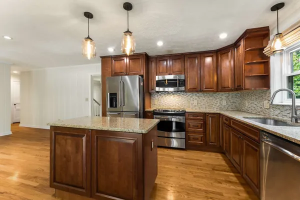 a kitchen with stainless steel appliances kitchen island granite countertop a sink refrigerator and cabinets