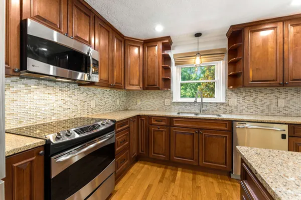 a kitchen with stainless steel appliances granite countertop a stove a sink and a microwave