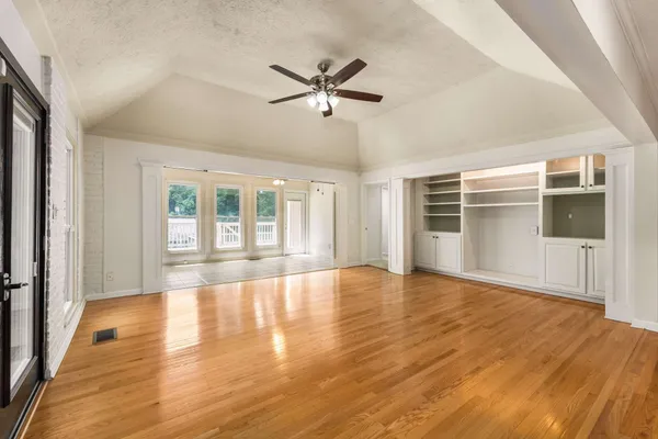 a view of empty room with wooden floor and fan