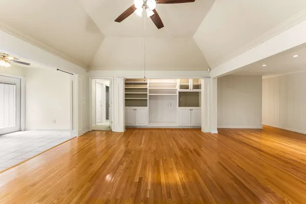 a view of empty room with wooden floor and fan