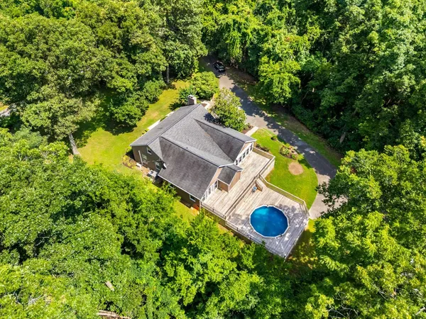 a house with swimming pool and trees in the background