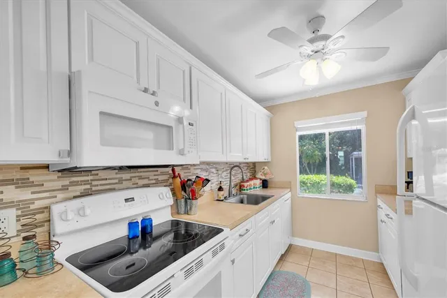 a kitchen with kitchen island granite countertop a stove a sink dishwasher and white cabinets with wooden floor