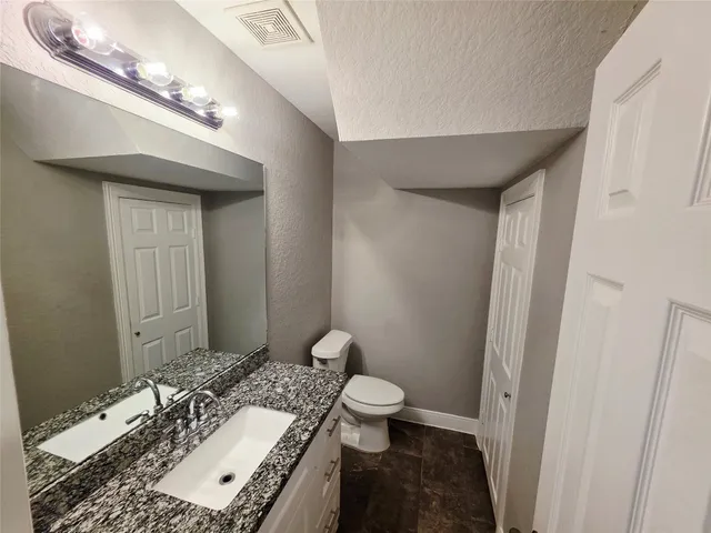 a bathroom with a granite countertop sink a toilet and a mirror