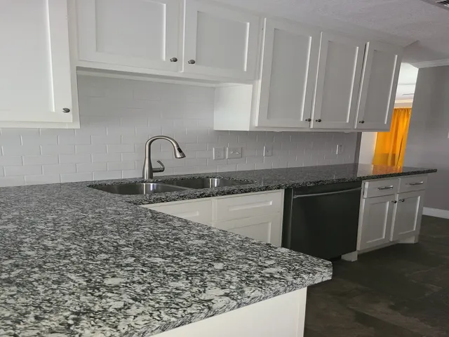 a kitchen with granite countertop a sink a stove and cabinets
