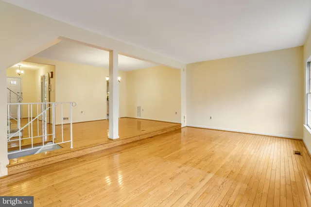 a view of an empty room with wooden floor and a bathroom