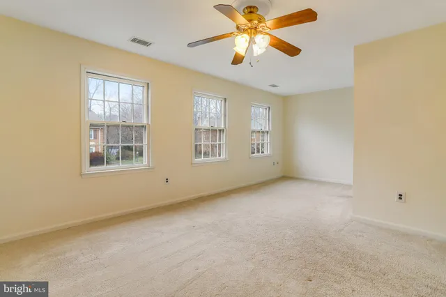 an empty room with windows and chandelier fan