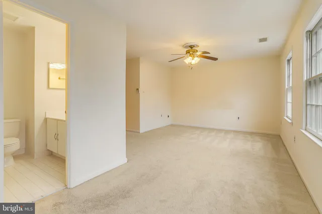 an empty room with a window and a ceiling fan