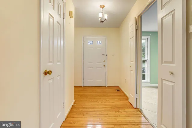 a view of a hallway with wooden floor and a bathroom