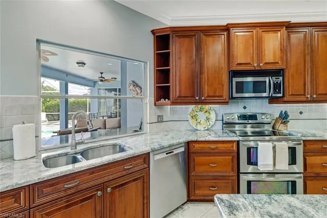 a kitchen with stainless steel appliances granite countertop a stove a sink and a microwave