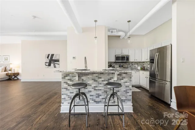 a kitchen with stainless steel appliances kitchen island granite countertop a refrigerator and a stove top oven