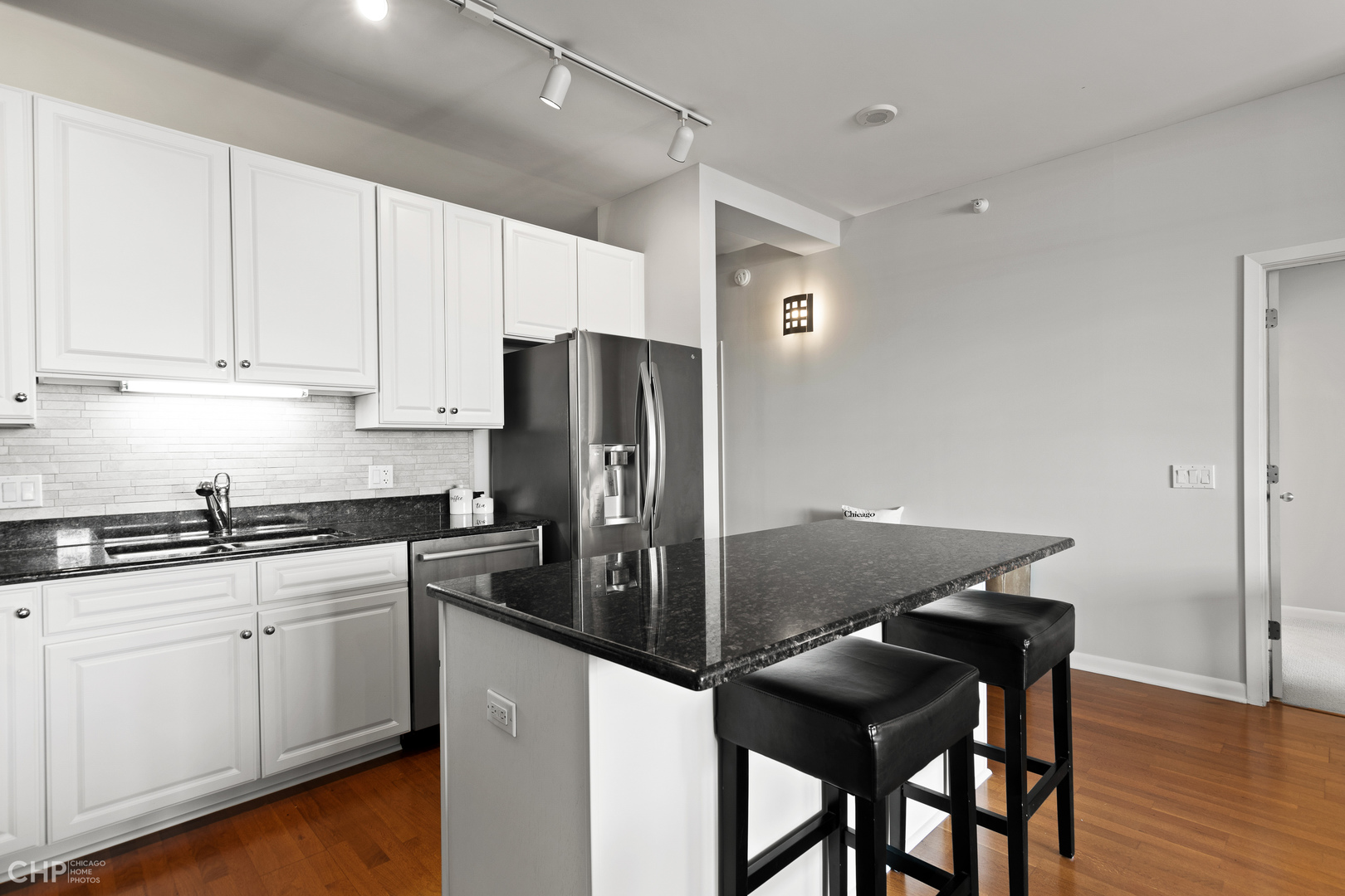 1200 West Monroe Street, Unit 805 Chicago, IL 60607 - Photo 7 of 18 a kitchen with stainless steel appliances kitchen island a table chairs in it and white cabinets