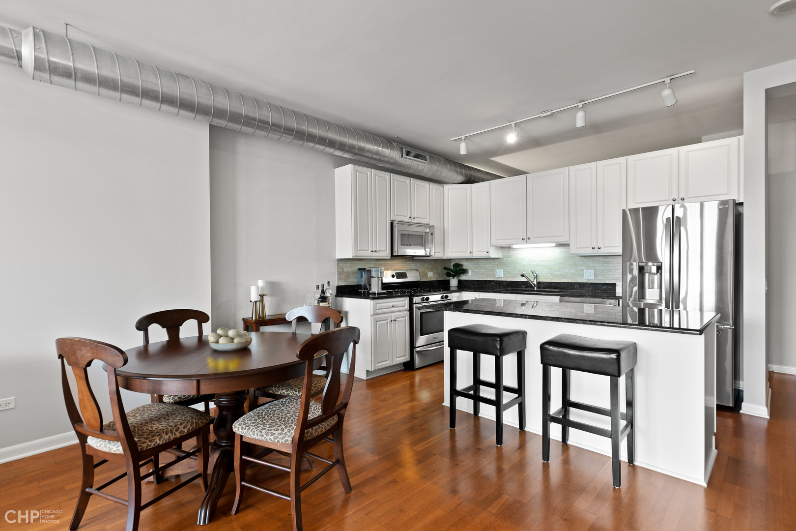 1200 West Monroe Street, Unit 805 Chicago, IL 60607 - Photo 8 of 18 a kitchen with stainless steel appliances granite countertop a dining table chairs stove refrigerator and cabinets