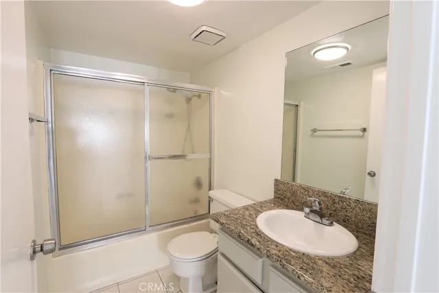 a bathroom with a granite countertop sink toilet mirror and a shower