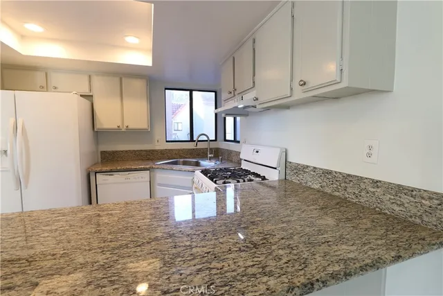 a kitchen with stainless steel appliances granite countertop a sink refrigerator and cabinets