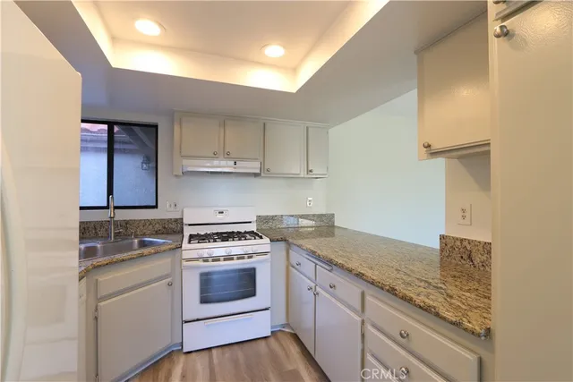 a kitchen with granite countertop a sink stove and cabinets