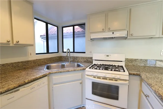 a kitchen with granite countertop a sink a stove and cabinets