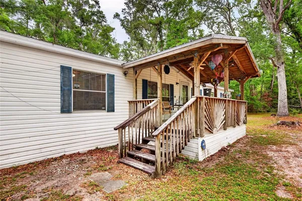 a view of a house with wooden deck next to a yard