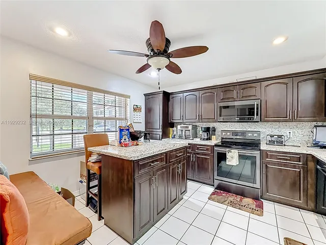 a kitchen with stainless steel appliances granite countertop a stove a sink dishwasher a dining table and chairs with wooden floor