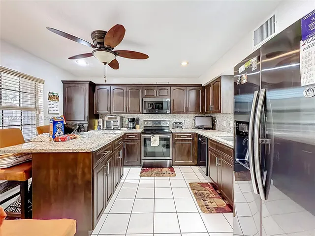 a kitchen with stainless steel appliances kitchen island granite countertop a sink dishwasher stove and refrigerator