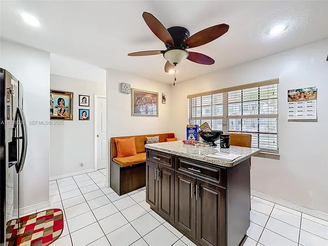 a view of a kitchen with kitchen island granite countertop a sink and a refrigerator